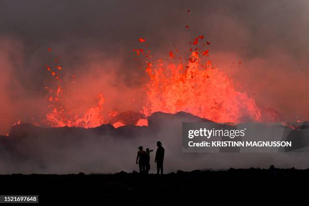 People watch flowing lava during an volcanic eruption near Litli Hrutur, south-west of Reykjavik in Iceland on July 10, 2023. A volcanic eruption...