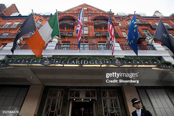 Doorman stands beneath flags as they fly above the entrance to Claridge's Hotel in London, U.K., on Monday, Sept. 17, 2012. Glencore's London office...
