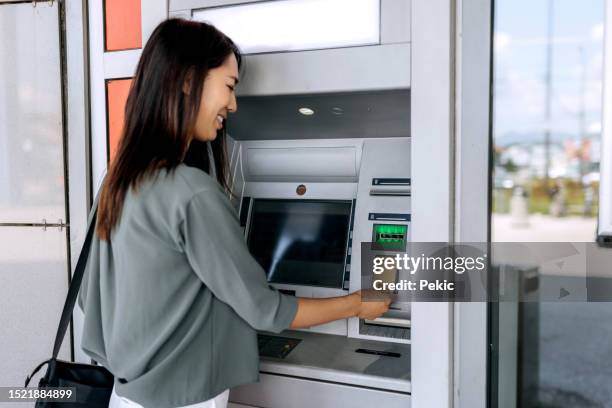 young casually clothed woman using atm machine - paid absence stock pictures, royalty-free photos & images