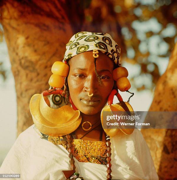 Fulah woman photographed at Mopti, She wears magnificent jewellery in the form of huge gold and amber hair decorations. Mali. 1962.