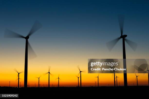 sunset over wind turbines,silhouette of wind turbines on field against sky during sunset - varna bulgaria stock pictures, royalty-free photos & images