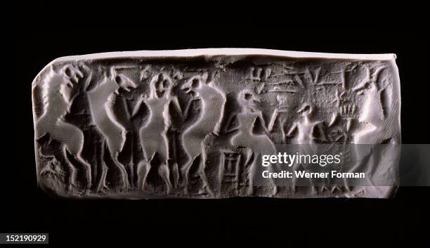 Modern impression of an early dynastic Sumerian alabaster cylinder seal, Inscribed with a scene of a seated figure being handed a beaker by an...