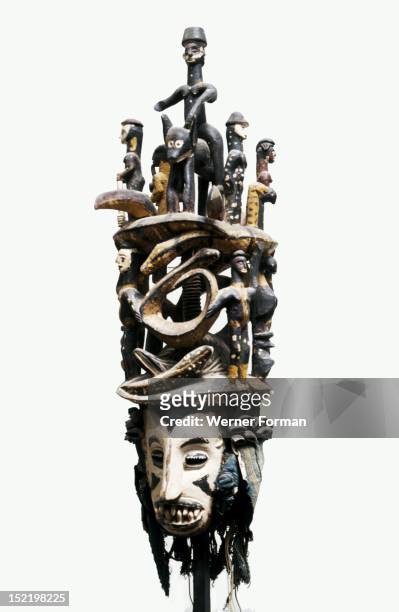 White faced Igbo mask with two tiered superstructure of polychromed figures, including a horse and rider and pythons, Nigeria. Igbo. 20th c...