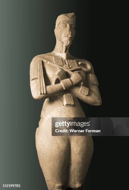 Colossal statue of Akhenaten standing with arms folded holding the flail and heka scepters, The lack of genitalia is thought to be a reflection of...