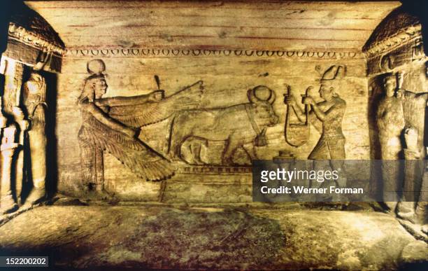 Offering scene with the sacred bull, Apis, The dead man is offering to the bull while Isis behind spreads her wings in protection. Apis served as the...