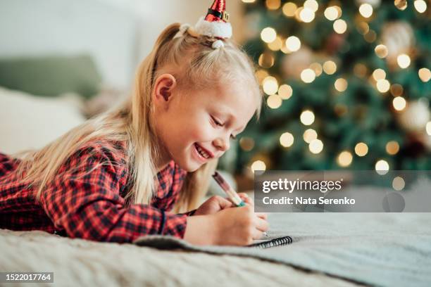 merry christmas and happy holidays! funny child girl writing letter to santa at home near christmas tree. - answering stock pictures, royalty-free photos & images