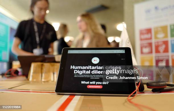 Tablet screen is displayed on red cross / red half moon stand on July 07, 2023 in Geneva, Switzerland. Red Cross and Red Half Moon organisations are...