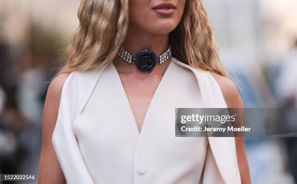 Emili Sindlev is seen wearing a diamond choker with a black rose on the front, a creme-white sleeveless waistcoat, a silver bracelet, chunky rings, a...