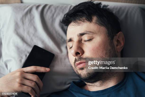 sleeping man with smartphone - overslept stockfoto's en -beelden