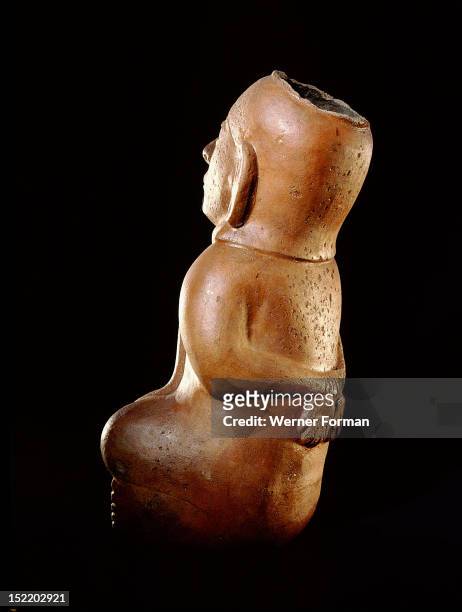 Mochica vessel in the form of a seated prisoner with his hands bound behind his back, A second rope is attached to both his neck and his penis. This...
