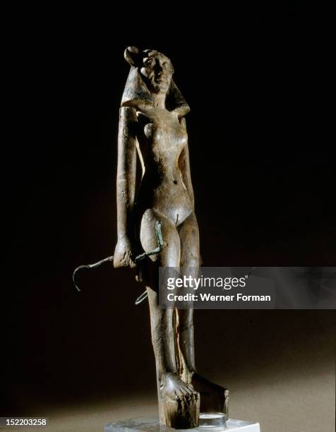 Figurine of a nude female dancer wearing a leonine mask, holding a bronze serpent in each hand, Found in a chest full of papyri bearing incantations...