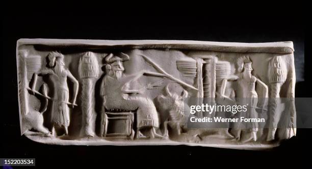 Modern impression of an Akkadian cylinder seal inscribed with a scene of a seated deity wearing horned headdress, with attendant and a recumbent bull...