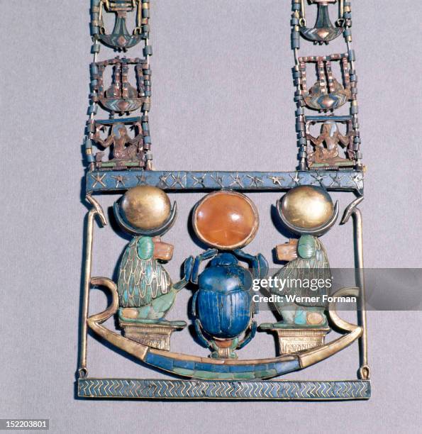 Pendant from the tomb of Tutankhamun, Two baboons with moon discs on their heads worship the sun god in scarab beetle form. He holds up a solar disc...