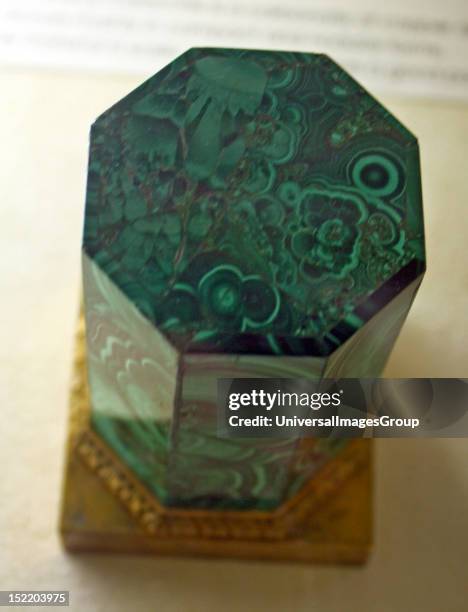 Malachite. A carved and polished octagonal column with a brass base.