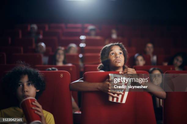 black girl watching a suspenseful movie in cinema. - filmfestival stock pictures, royalty-free photos & images