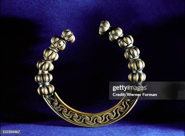 An unusual type of torque which seems to be modelled on necklaces made of large pearls decorated with mouldings, The relief decoration on the rigid...