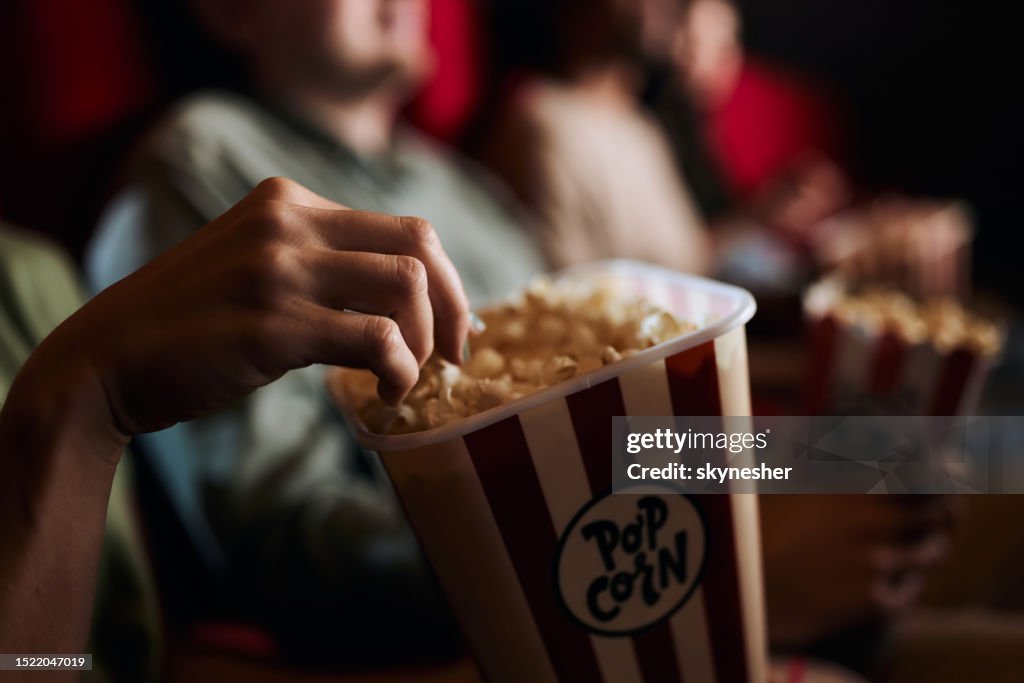 Close up of eating popcorn in cinema.