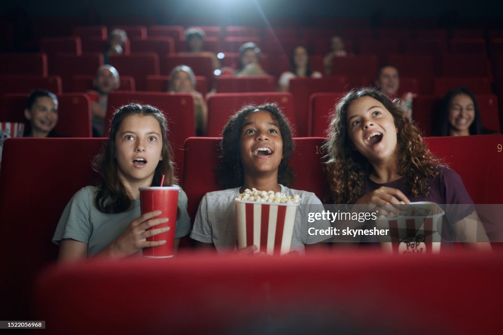 Happy girls watching a surprising movie in theatre.