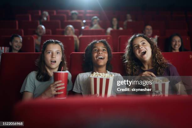 happy girls watching a surprising movie in theatre. - cinema stock pictures, royalty-free photos & images