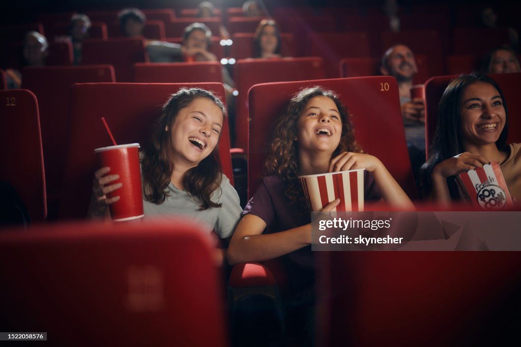 Cheerful little friends watching comedy movie in theatre.