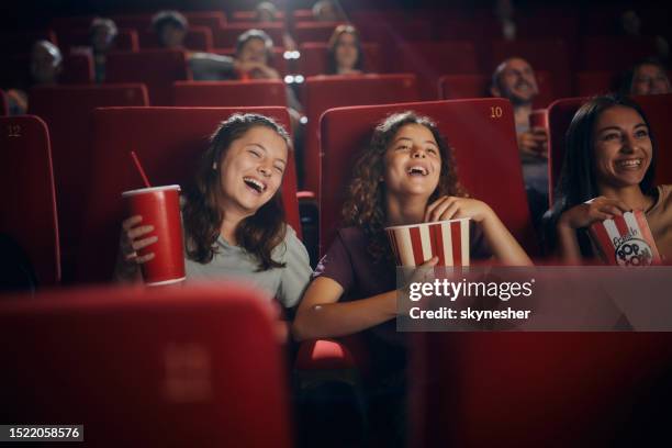 cheerful little friends watching comedy movie in theatre. - movie cinema stock pictures, royalty-free photos & images