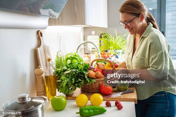 mujer con cesta llena de verduras frescas en la cocina - comida sana fotografías e imágenes de stock