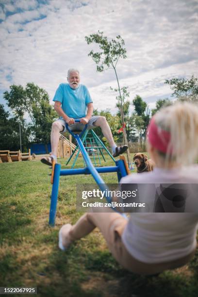 happy senior having fun at the playground riding seesaw - see saw stock pictures, royalty-free photos & images