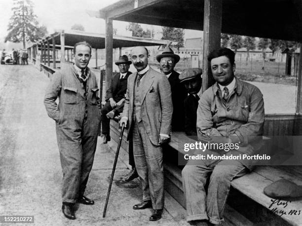 Italian engineer and entrepreneur Nicola Romeo posing in the racetrack pits with Italian racing driver Enzo Ferrari, Italian engineer Giuseppe Morosi...