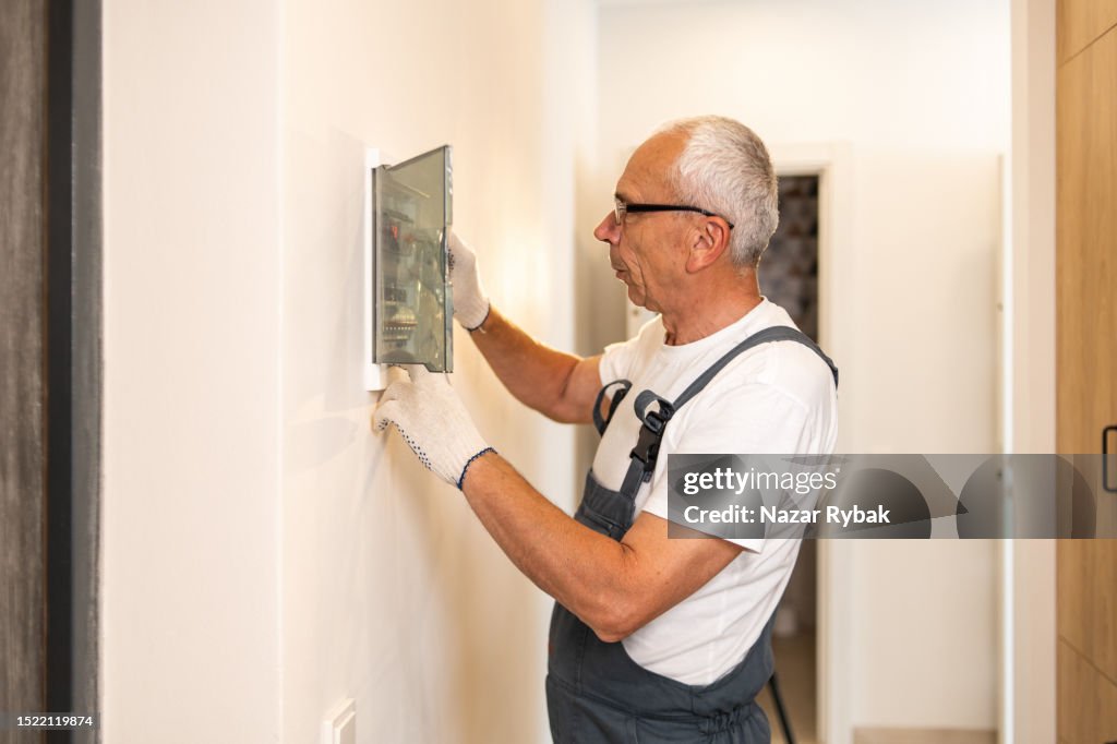 An electrician works at the switchboard at home