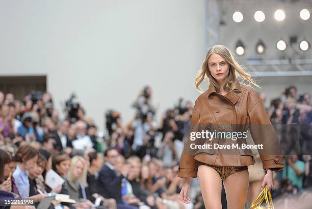 Model Cara Delevingne walks the runway at the Burberry Spring Summer 2013 Womenswear Show at Kensington Gardens on September 17, 2012 in London,...