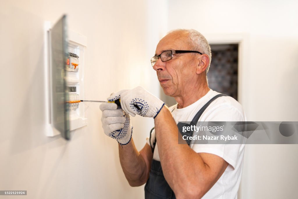 Ein professioneller Elektriker wartet eine elektrische Schalttafel zu Hause