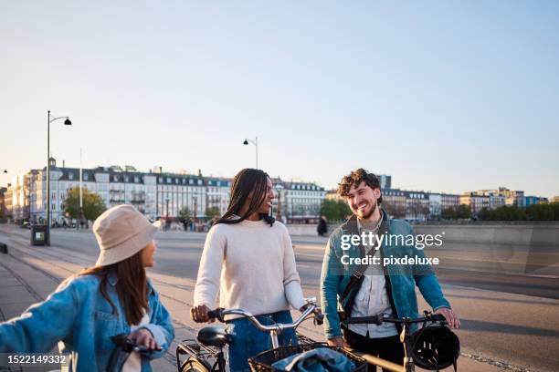 cityscape connection: multi-ethnic friends create memorable moments through cycling - engaged sunset stockfoto's en -beelden