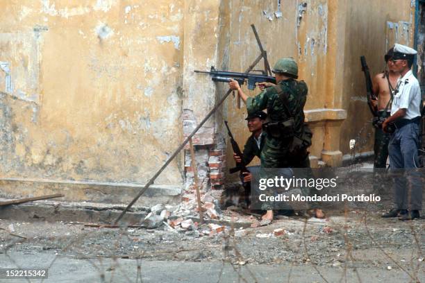 Some soldiers and South Vietnamese policemen are fighting behind a building. Saigon , 1968.