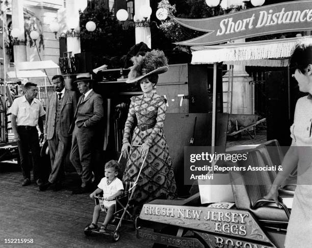 Barbra Streisand, who plays the role of Dolly Levi in the movie Hello, Dolly, wheels her son Jason Gould's baby buggy on the set of the film. USA,...