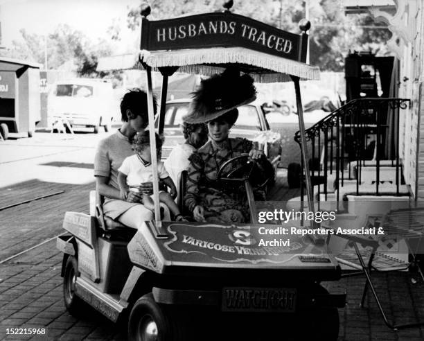 Barbra Streisand driving a buggy and her son Jason Gould in his baby sitter arms on the set of Hello, Dolly. USA, 1968.