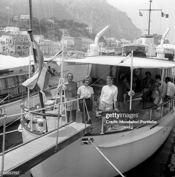 The actress Ingrid Bergman and her daughter Pia Lindstrom with some friends inside a yacht berth on the pier. Capri, the '50s.