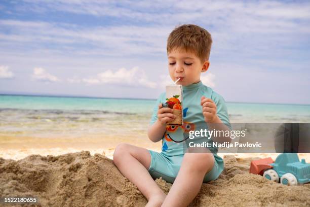 little boy drinking juice on the beach - juice box stock pictures, royalty-free photos & images