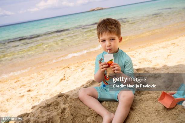 little boy drinking juice on the beach - juice box stock pictures, royalty-free photos & images