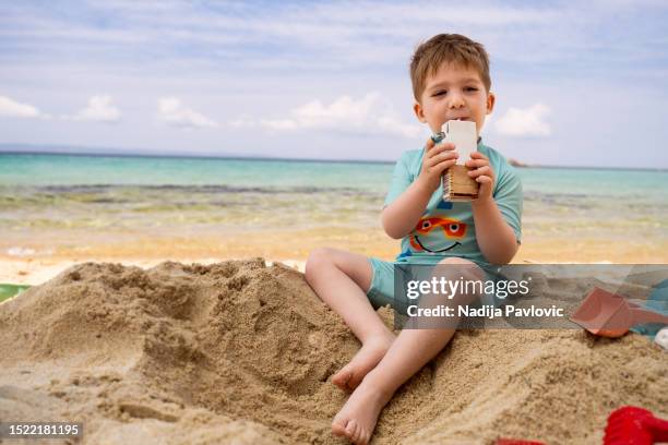 little boy drinking juice on the beach - juice box stock pictures, royalty-free photos & images