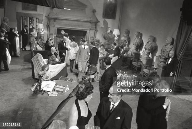 Scene from the movie 'La Dolce Vita' in the living room of the castle, where actors take position; among them, Marcello Mastroianni, while peeps out...