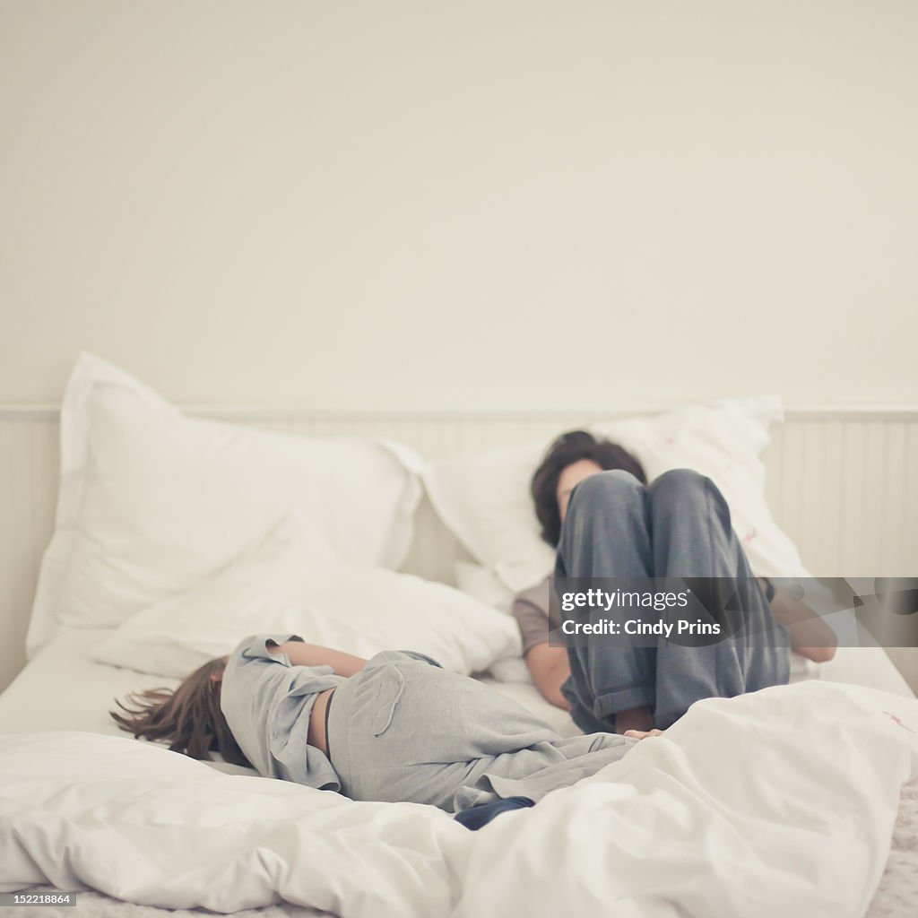 Two boys relaxing on a white bed