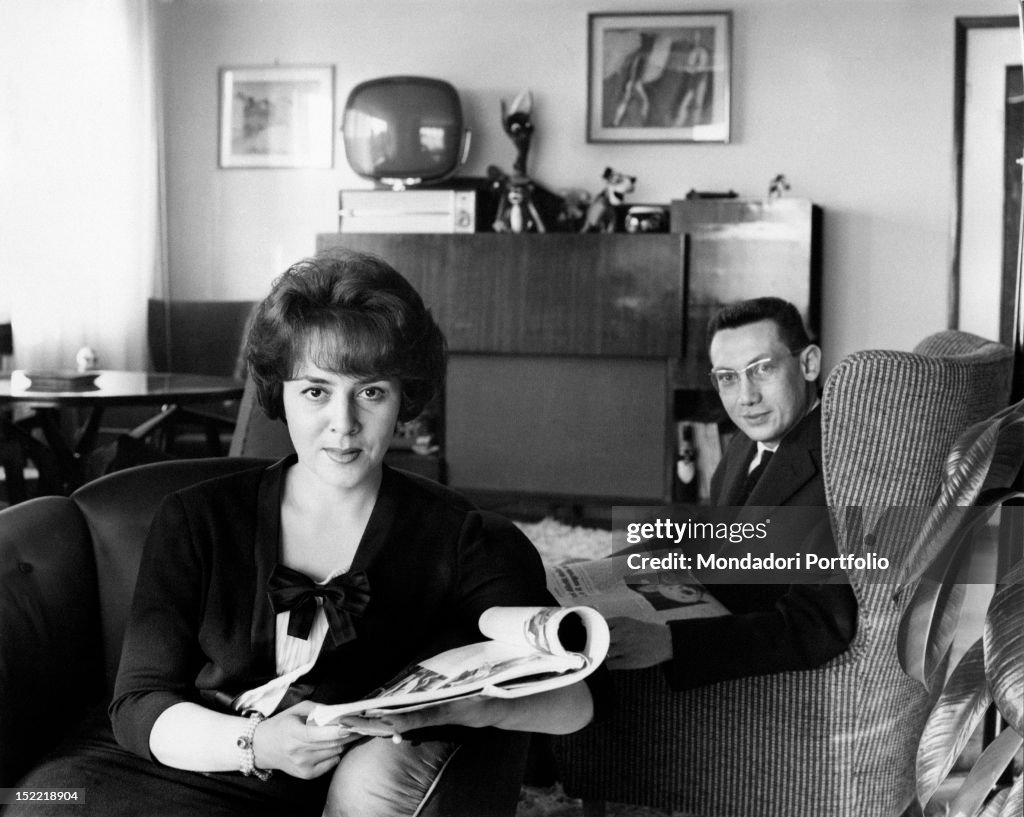 Jula De Palma and Carlo Lanzi are sat on armchairs with a newspaper in their hands