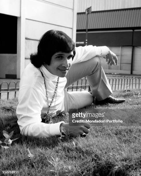 The Brasilian singer Roberto Carlos is posing, lying on a flower-bed during a stay in Milan. Milan, July, 1968.