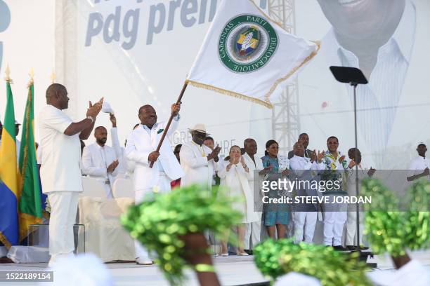 Gabon President Ali Bongo Ondimba waves the Gabonese Democratic Party flag at the Nzang Ayong stadium in Libreville on July 10 a day after he...