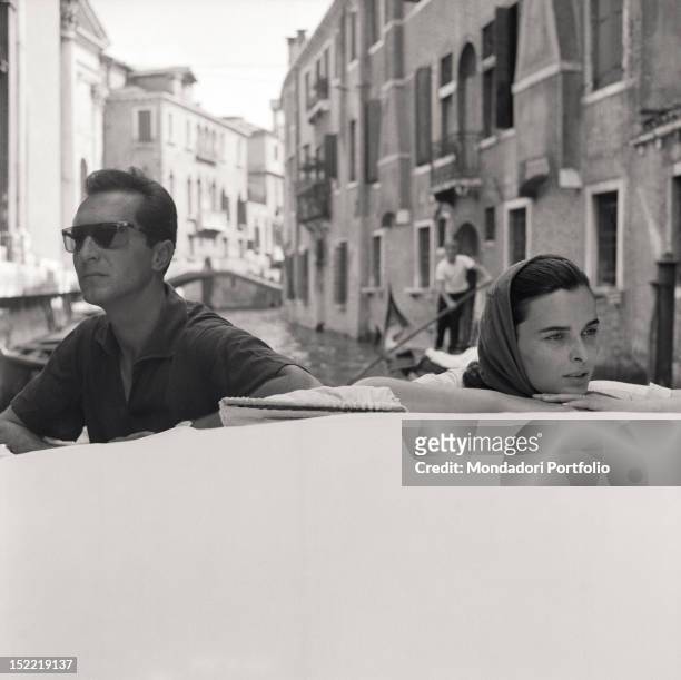 Lucia Bosè and her bullfighter husband Luis Miguel Dominguin are on a boat in a small canal of the Venetian lagoon, they both are completely absorbed...