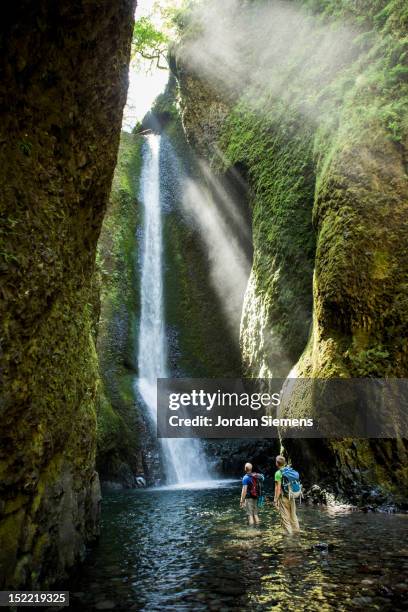two men hiking to a waterfall. - turismo ecológico fotografías e imágenes de stock