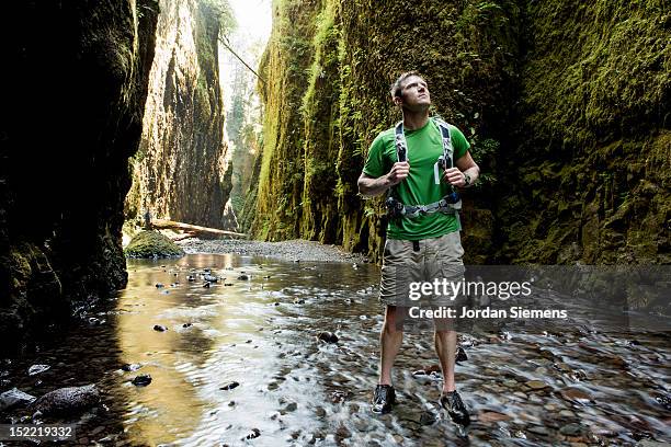 a man hiking a narrow canyon filled with water. - portland oregon columbia river gorge stock pictures, royalty-free photos & images