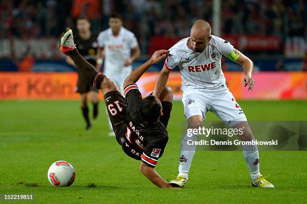 Miso Brecko of Cologne steps on the hand of Mahir Saglik of St. Pauli as they battle for the ball during the Second Bundesliga match between 1. FC...