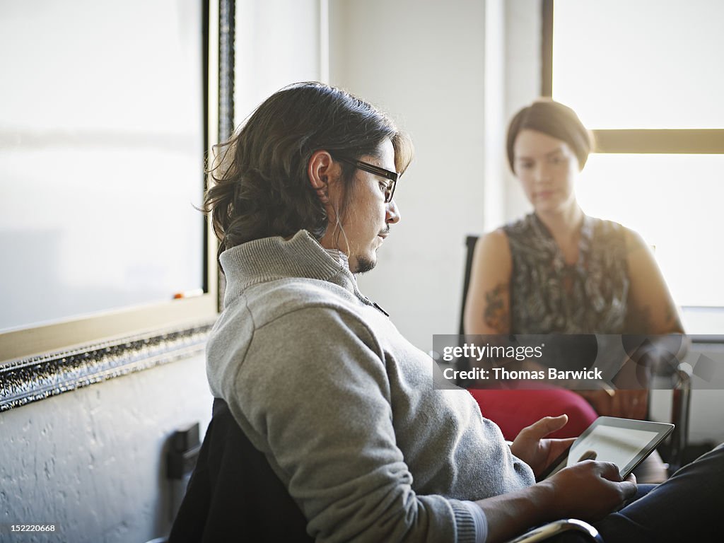 Businessman sitting at desk using digital tablet