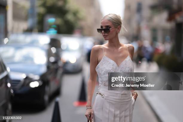 Leonie Hanne is seen wearing a complete Fendi outfit consisting of golden sunglasses with brown lenses, a white lacy top, white suit pants with a...